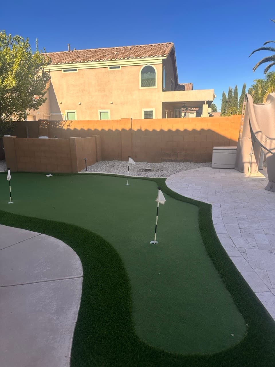 Completed putting green with travertine surround in a Mesa, AZ backyard