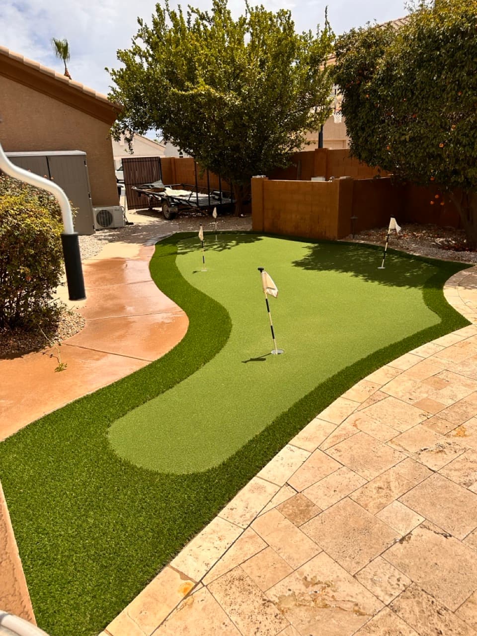 Putting green installation with travertine patio surround in Mesa, AZ
