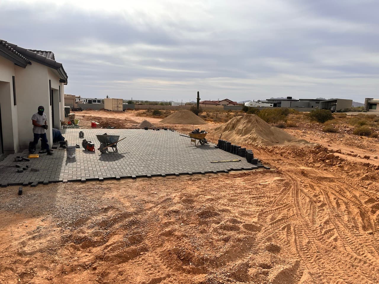 Paver patio being laid with wheelbarrow and crew on site